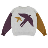 Lucky Bird Sweater van Jenest voor jongens, met contrasterende mouwen in plum en hazelnut en een zwaluw-patch op de rug. | Verkrijgbaar bij Little Fashion Addict